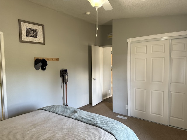 bedroom with dark colored carpet, a closet, ceiling fan, and a textured ceiling
