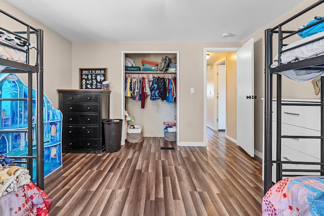 bedroom featuring baseboards, wood finished floors, and a closet