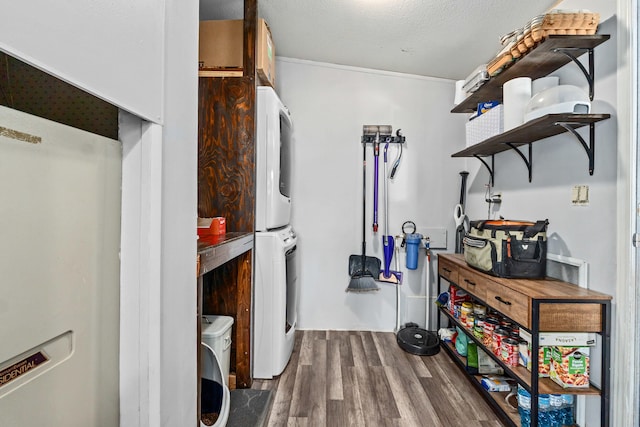 washroom with stacked washer and clothes dryer, wood finished floors, and laundry area