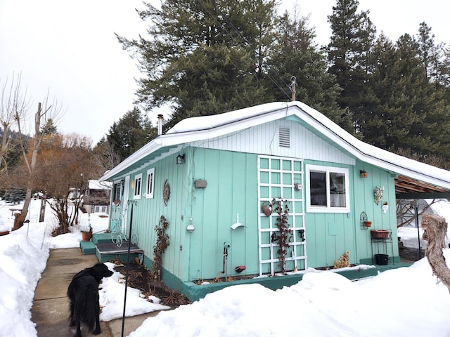 snow covered structure with an attached carport