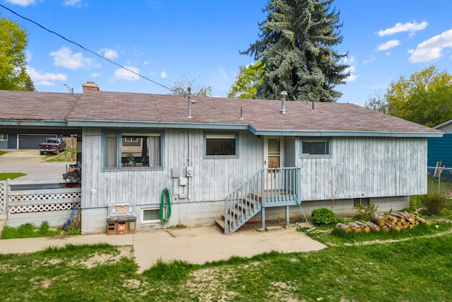 rear view of property featuring a lawn, a chimney, and fence