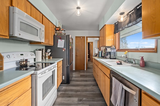 kitchen with brown cabinets, a sink, dark wood-type flooring, light countertops, and appliances with stainless steel finishes