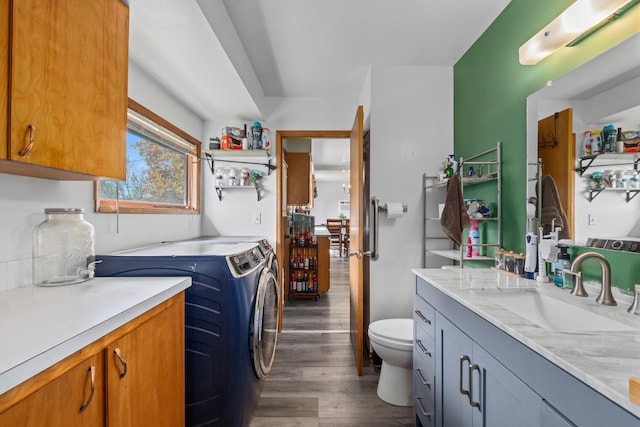 clothes washing area featuring a sink, dark wood-style flooring, independent washer and dryer, and laundry area