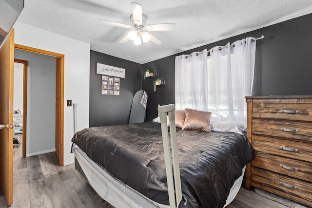bedroom with a textured ceiling, wood finished floors, and ceiling fan