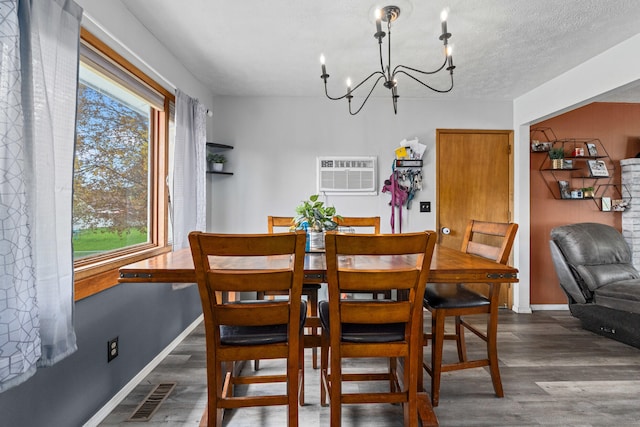 dining space featuring a wall unit AC, a chandelier, visible vents, baseboards, and wood finished floors