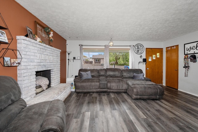 living area with a textured ceiling, wood finished floors, and a brick fireplace