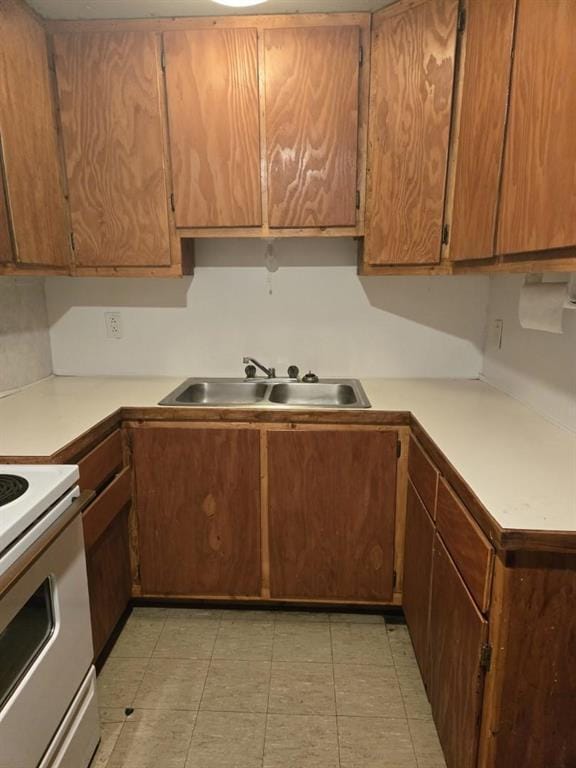 kitchen featuring a sink, light tile patterned floors, light countertops, and electric range
