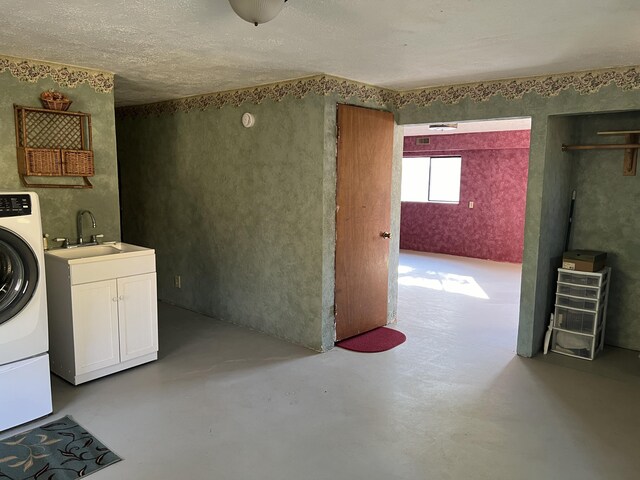 clothes washing area featuring sink, washer / dryer, and cabinets