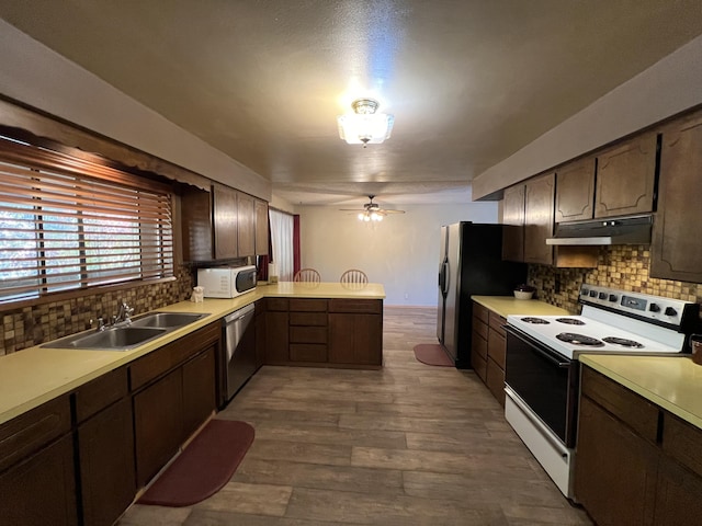 kitchen featuring ceiling fan, white appliances, sink, kitchen peninsula, and backsplash