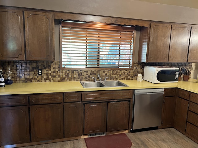 kitchen with sink, backsplash, dishwasher, and dark brown cabinetry