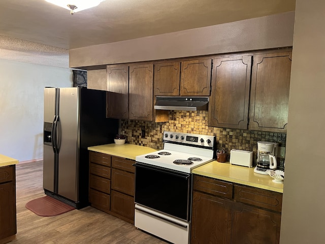 kitchen featuring stainless steel refrigerator with ice dispenser, dark brown cabinetry, decorative backsplash, and range with electric cooktop