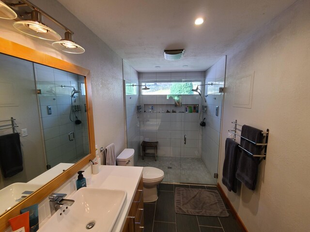 bathroom featuring a shower with shower door, toilet, vanity, and tile patterned flooring