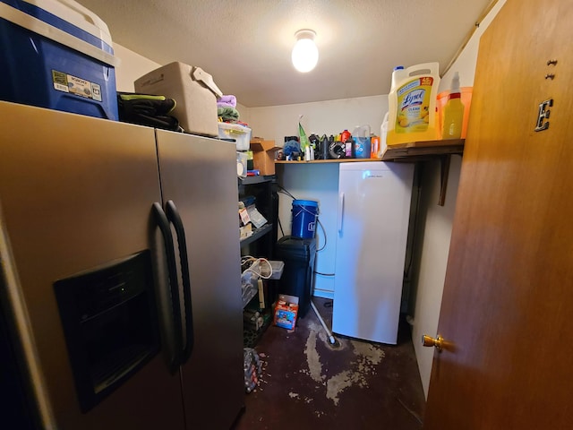 kitchen with a textured ceiling, stainless steel fridge with ice dispenser, refrigerator, and concrete flooring