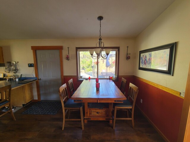 dining space featuring dark wood-type flooring and a notable chandelier