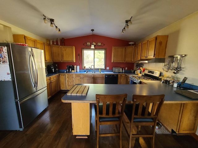 kitchen featuring kitchen peninsula, pendant lighting, vaulted ceiling, appliances with stainless steel finishes, and dark wood-type flooring