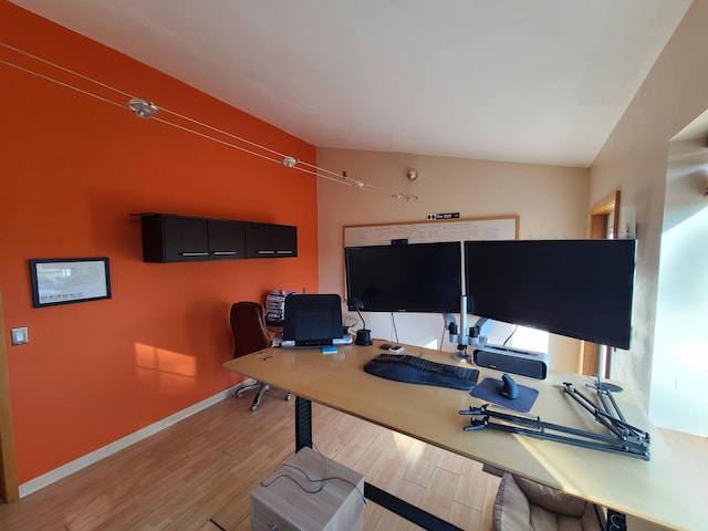 home office with light hardwood / wood-style floors and vaulted ceiling