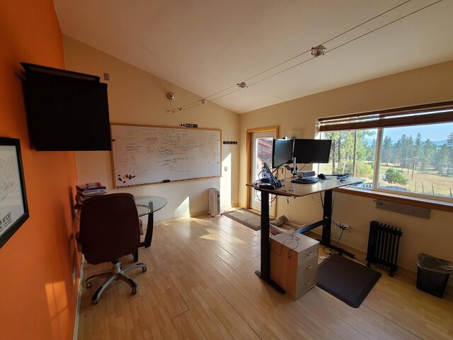 office featuring radiator heating unit, light hardwood / wood-style floors, and lofted ceiling