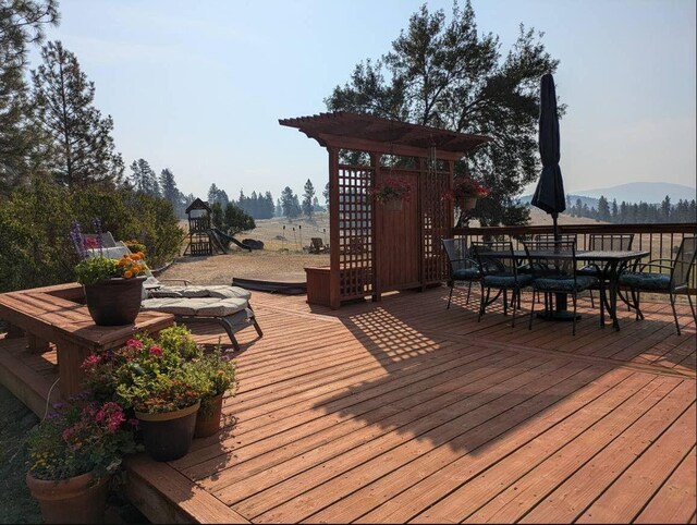 wooden deck featuring a playground and a mountain view