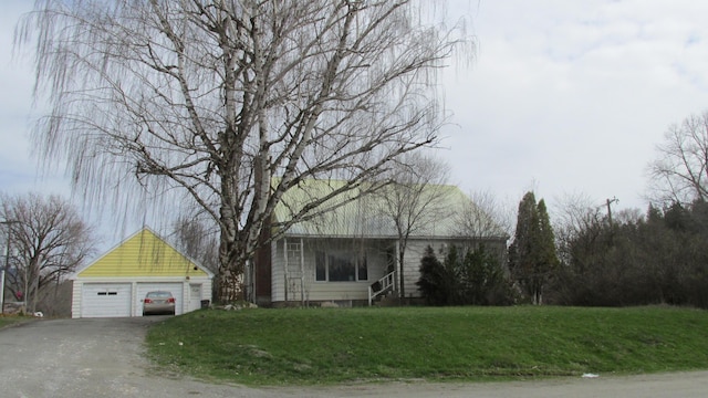 view of front of house with a garage, a front yard, and an outbuilding