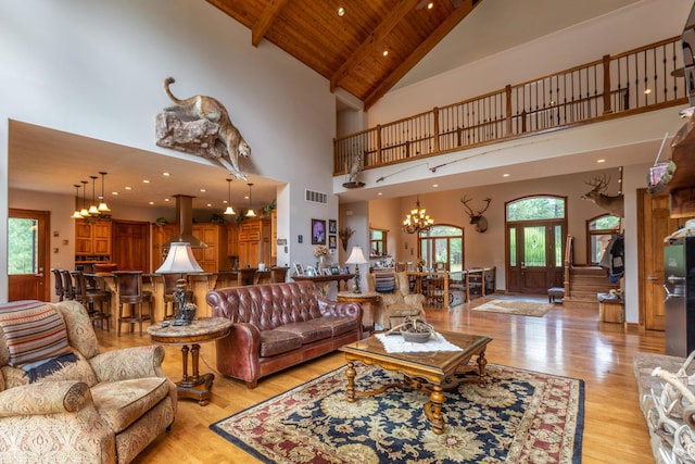 living room featuring wood ceiling, high vaulted ceiling, light hardwood / wood-style floors, a chandelier, and beamed ceiling