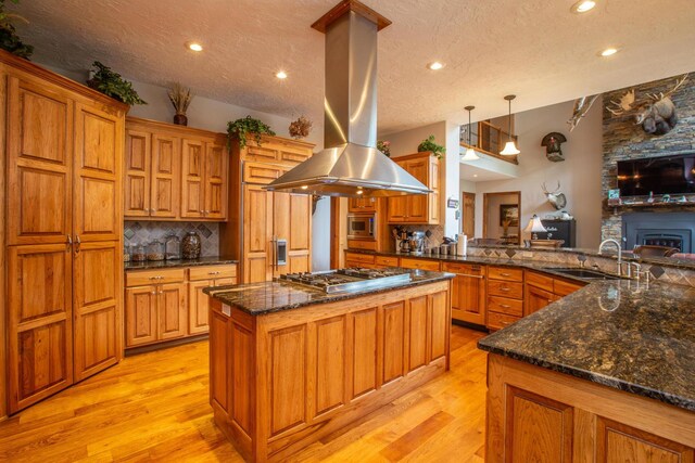 kitchen with pendant lighting, appliances with stainless steel finishes, sink, kitchen peninsula, and island range hood