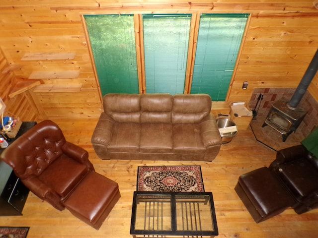 living area with wood walls, a wood stove, and wood finished floors