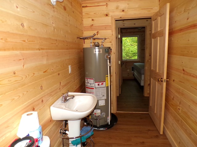 bathroom with wooden walls, wood finished floors, and water heater