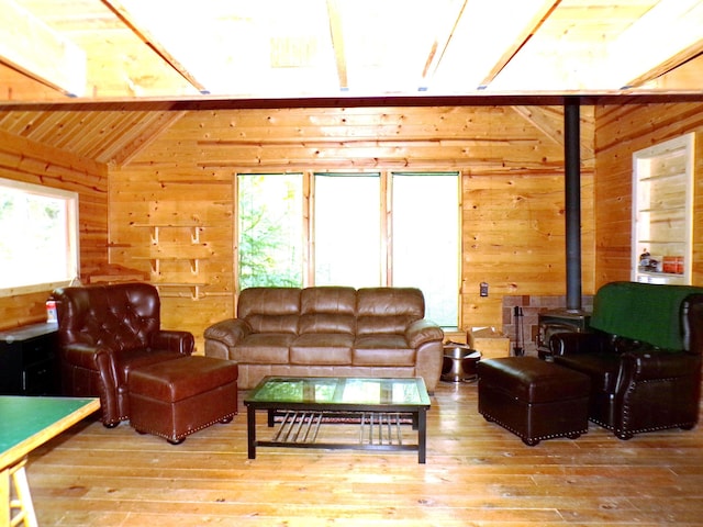 living room with hardwood / wood-style floors, lofted ceiling, wood ceiling, a wood stove, and wood walls