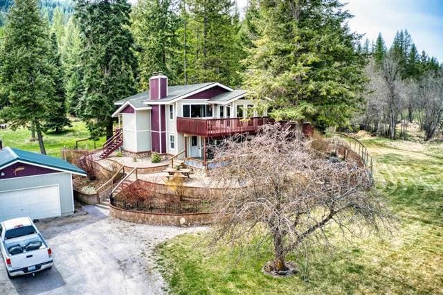 view of front of property with an outdoor structure, a wooden deck, a garage, and a front lawn