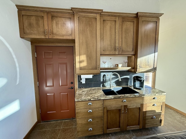 kitchen featuring dark tile patterned floors, sink, and stone counters