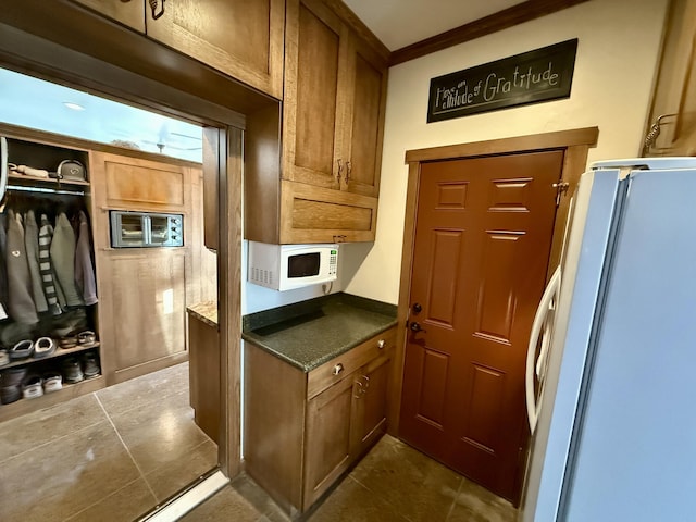 kitchen with ornamental molding and white appliances