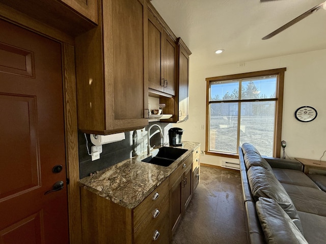 kitchen featuring stone counters, a baseboard radiator, sink, and decorative backsplash