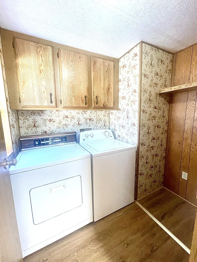 laundry room featuring hardwood / wood-style floors, cabinets, a textured ceiling, and washing machine and clothes dryer