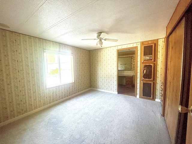 carpeted spare room with ceiling fan and a textured ceiling