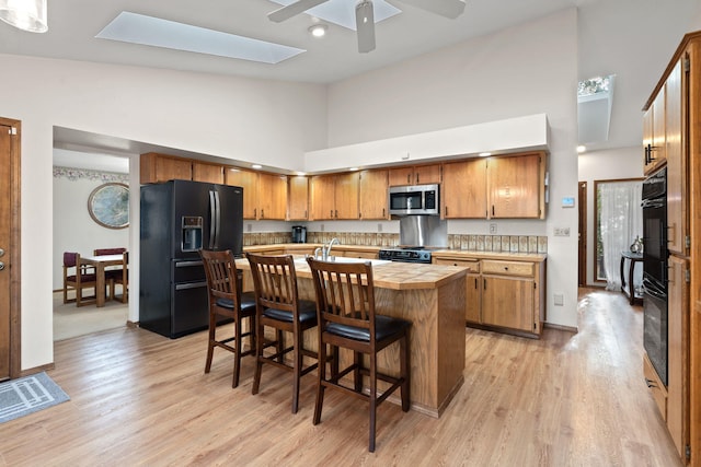 4203 S Suncrest Ln, Spokane Valley, WA 99037 - kitchen with black appliances, high vaulted ceiling, light wood-style floors, a ceiling fan, and a breakfast bar