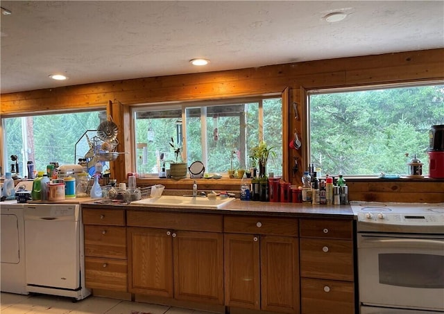 kitchen with sink, a wealth of natural light, white appliances, and light tile patterned floors