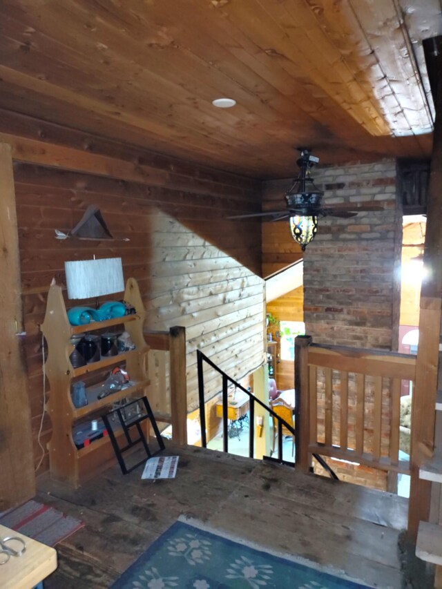 interior space featuring wood ceiling, ceiling fan, and wood walls