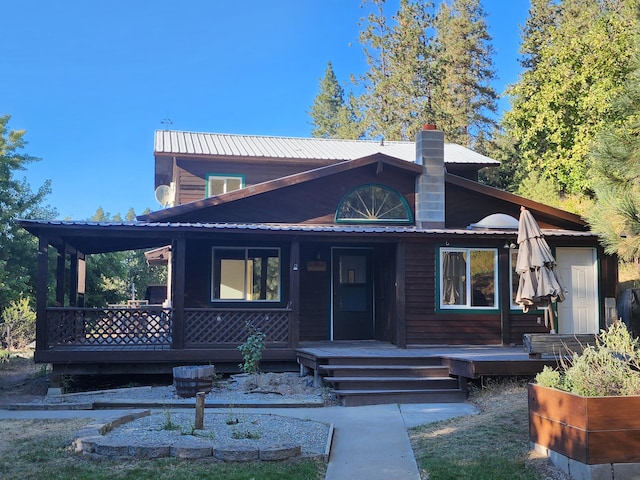 view of front of house with metal roof, covered porch, and a chimney
