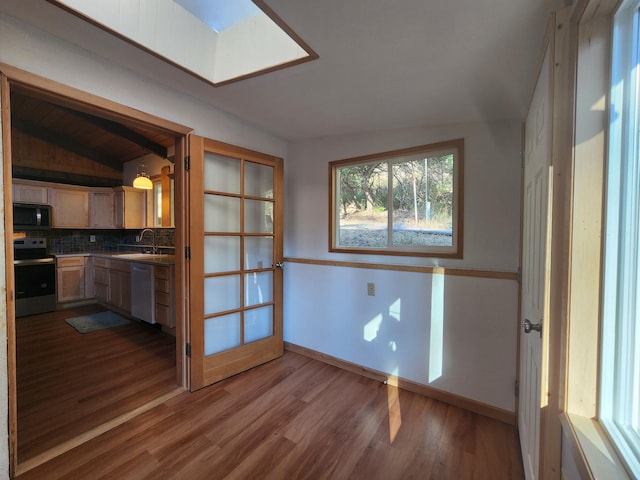 unfurnished dining area with baseboards, vaulted ceiling, a sink, and wood finished floors