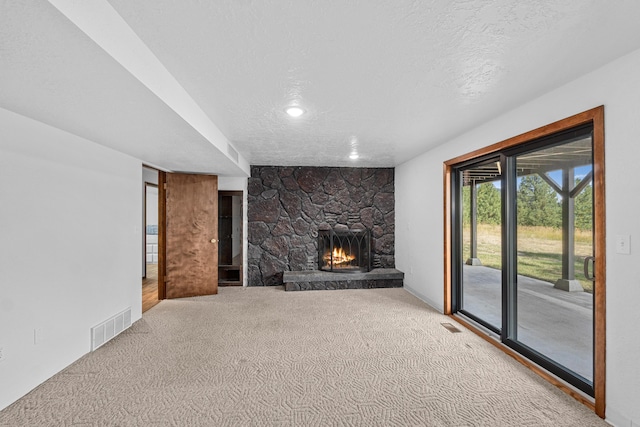 unfurnished living room featuring a fireplace, a textured ceiling, and carpet