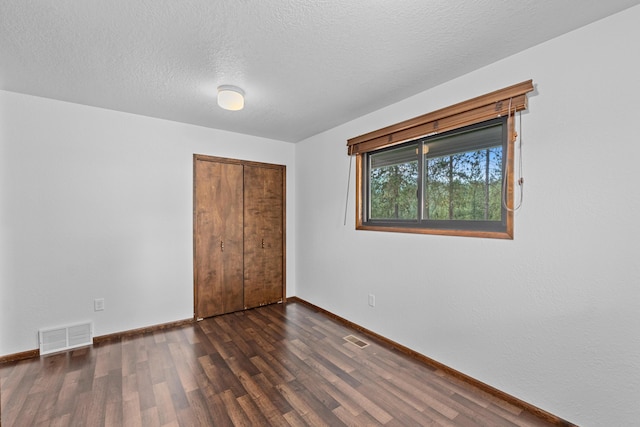 unfurnished bedroom with a closet, dark hardwood / wood-style floors, and a textured ceiling