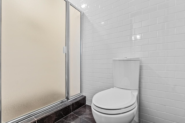 bathroom with a shower with shower door and toilet