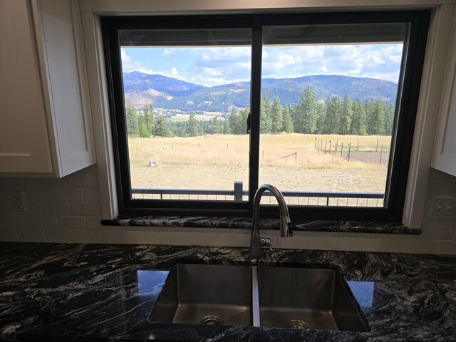 kitchen featuring sink, white cabinetry, tasteful backsplash, and a mountain view