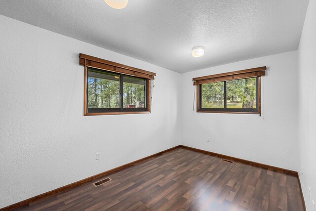 unfurnished room with a textured ceiling and dark hardwood / wood-style flooring