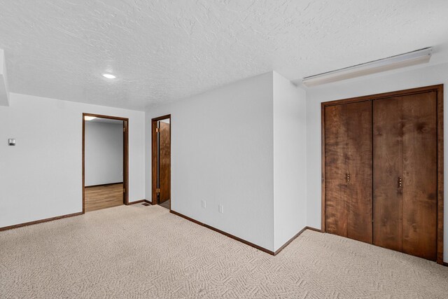 unfurnished bedroom featuring a textured ceiling, a closet, and light carpet