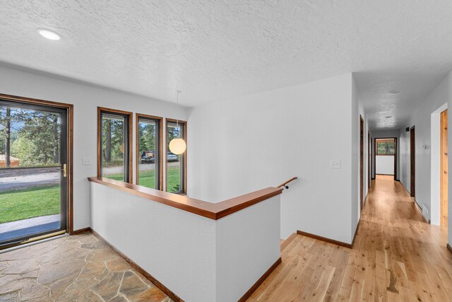 hall featuring light hardwood / wood-style flooring and a textured ceiling