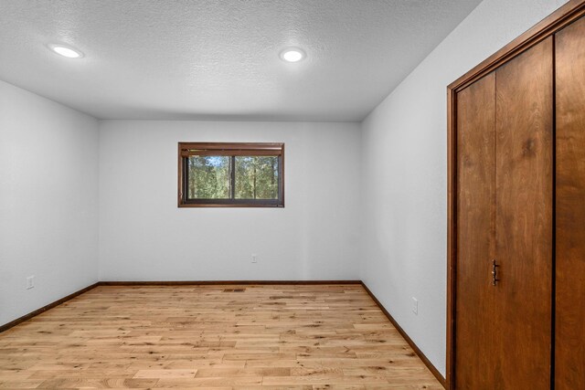 spare room with a textured ceiling and light hardwood / wood-style flooring