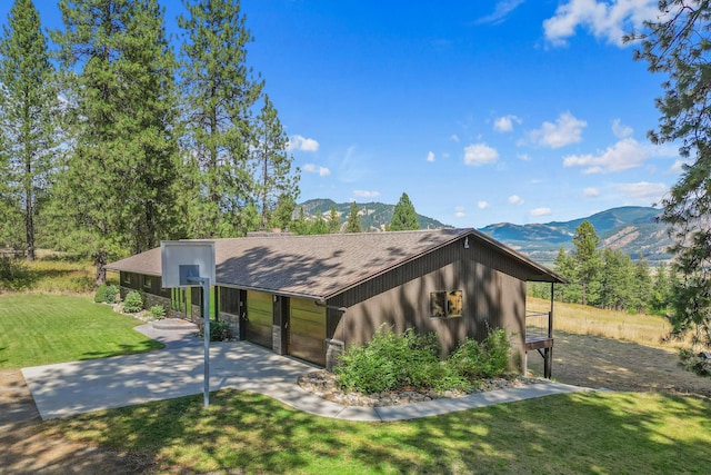 view of front facade featuring a garage, a mountain view, and a front lawn