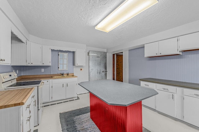 kitchen with white electric range, a center island, white cabinets, and sink