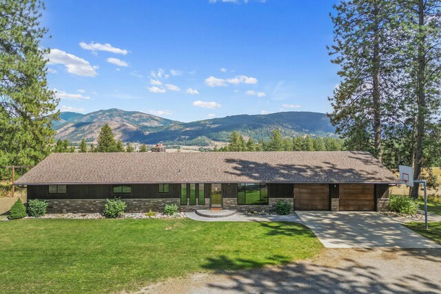 ranch-style house featuring a mountain view, a front lawn, and a garage